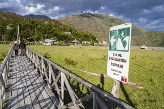 Signpost showing evacuation route in case of a tsunami, wooden boardwalk of Caleta Tortel, Aysen