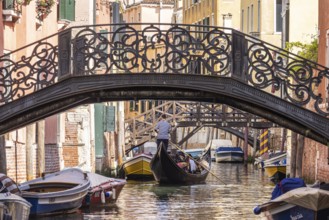 Venetian gondola with gondolier travelling on the canals of Venice, Venice, Italy, Europe