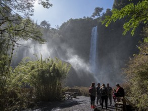 Tourists in front of waterfall Salto El Leon, valley of waterfalls east of Pucon, La Auracania,