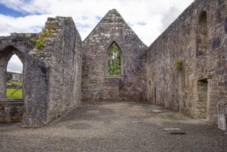 Gothic stone ruins with open walls and windows under a cloudy sky, Urlaur Abbey