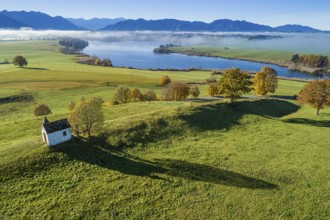 Aerial view of a small chapel in front of a lake, mountain landscape, autumn, sunny, Riegsee,