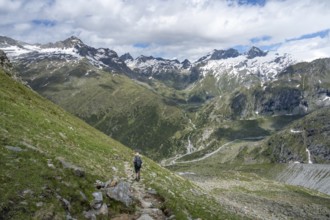 Mountaineer on a hiking trail in front of a picturesque mountain landscape, rocky mountain peaks