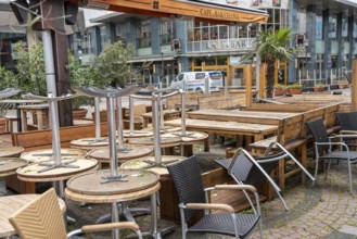 Stacked chairs and tables from various catering establishments, on Kennedyplatz, closed cafes,