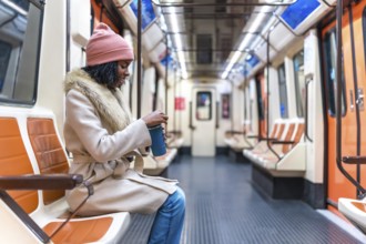 Passenger opening a reusable coffee cup while enjoying a quiet moment on a nearly empty subway