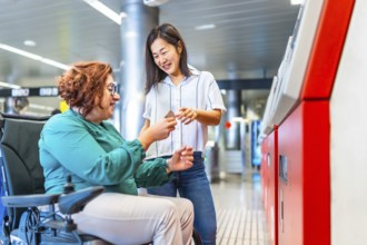 Chinese smiling caregiver buying metro ticket to a caucasian adult disabled woman in wheelchair