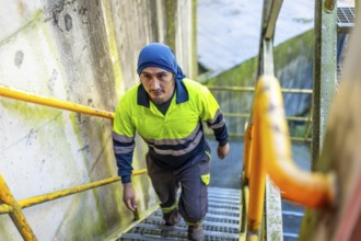 Top view of a latin man worker walking up stairs outside a recycling plant building