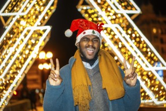 Portrait of a fun cool african young casual man gesturing success wearing a Santa hat at night in