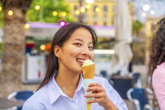 Close-up of a smiling chinese woman eating an ice cream in the city