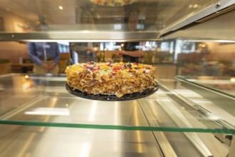 An artistically decorated cake with almond slivers and fruit in a glass display case, Cafe Kuh,