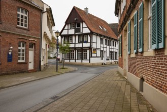 Historic brick houses with white windows and shutters and a small half-timbered house in Warendorf,