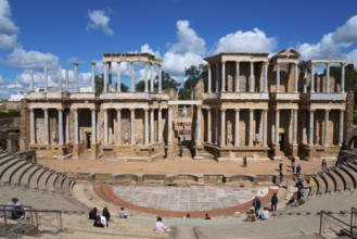 Large Roman theatre with impressive ancient columns and numerous spectators in the rows of seats