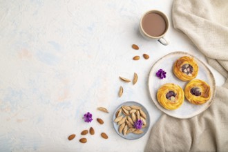 Small cheesecakes with jam and almonds with cup of coffee on a white concrete background and linen