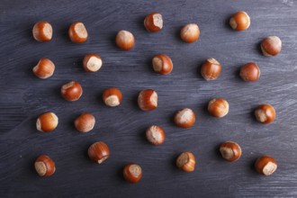 Pattern and texture made from hazelnuts on black wooden background, flat lay. top view