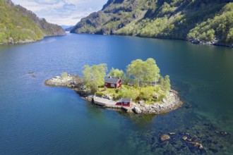 Typical red norwegian cottage on a little island in the fjord, aerial view, Lovrafjord, Norway,