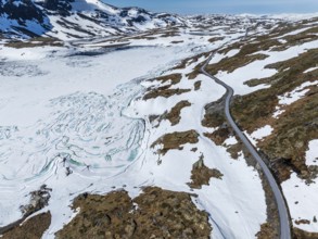 Aerial view of mountain crossing Sognefjellsvegen, along frozen lake Prestesteinsvatnet,