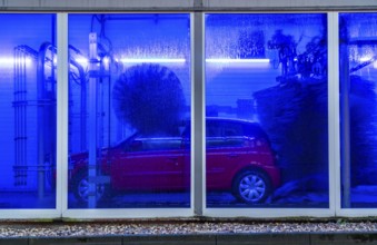Car in an automatic car wash, car wash tunnel, cleaning foam is sprayed on, rotating brushes clean