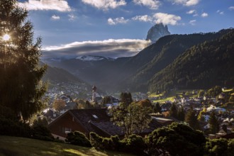 The mountain village of Ortisei in Val Gardena at sunrise, surrounded by wooded mountains and