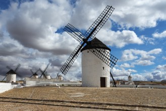 Row of white windmills on a sandy ground with a cloudy sky, Campo de Criptana, Ciudad Real