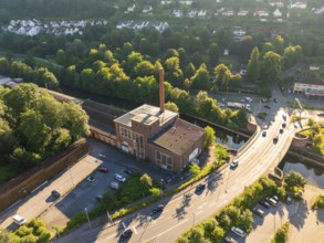 Aerial view of an industrial building on a street in an urban environment with lots of greenery and