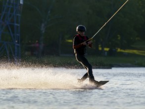 Young man with wakeboard in lake, water sports, water skiing in wakepark