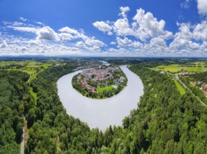 Aerial view of a village surrounded by a river, embedded in a vast green landscape under a cloudy