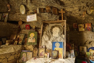 Altar area in a rock cave, surrounded by various crosses and religious symbols and icons, rock