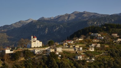 A small village in the mountains with a striking church at sunset, surrounded by mountains, Lakki