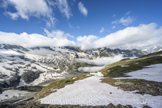 Mountain landscape with snow fields and high fog in the valley, summit Hoher Weißzint and