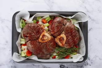 Fried meat on the bone, raw, chopped vegetables, ingredients in the oven, for cooking ossobuco, top