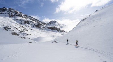 Atmospheric clouds in a wintry mountain landscape, ski tourers on the ascent to Porta d'Es-cha,