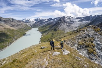 Two mountaineers on the summit of Mont de la Blana, view of a blue mountain lake, Lac des Dix