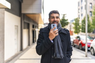 Adult caucasian man in winter elegant clothes sending voice message while walking along the street