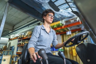 Concentrated cacuasian adult woman working with forklift in a warehouse of a metallurgic factory