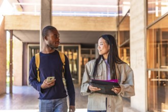 Frontal photo of two multiracial students talking walking along university