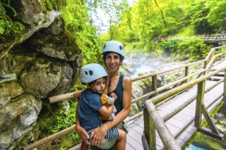 Mother holding her son while exploring the beautiful vintgar gorge near bled in slovenia, both