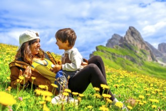 Tourists relaxing in a dandelion field, enjoying the view of the seceda mountains in the italian