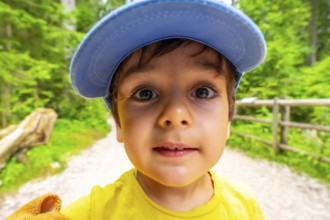 Close up of a child wearing a blue cap taking a selfie while enjoying a summer day in the dolomites