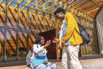 Two African female and male friends greeting each other upon arriving at the university campus
