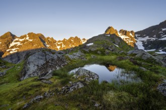 Rocky mountain peaks with reflection, small pond in moor landscape at Trollfjord Hytta, mountain