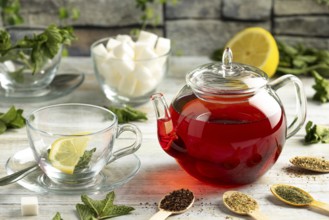Touched teapot, glasses with mint, sugar pieces, different types of tea and lemons