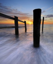 Sunset on the beach at Darßer Ort, fence and posts on the Baltic Sea as the border of the