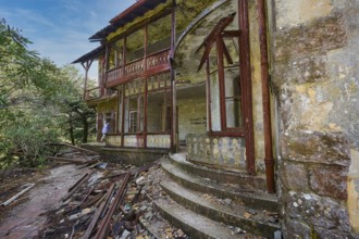 Sky replaced, Abandoned, damaged house with wooden structure, stone staircase and surrounding
