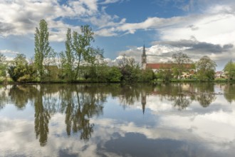 Huttenheim village reflected in a natural tree-lined river in spring. Bas Rhin, Alsace, France,