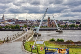 Modern bridge over a river in cloudy weather, in the background a city, Londonderry