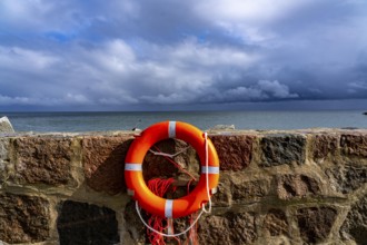 The city harbour of Sassnitz, island of Rügen, pier, harbour dam, dark rain clouds, lifebuoy,