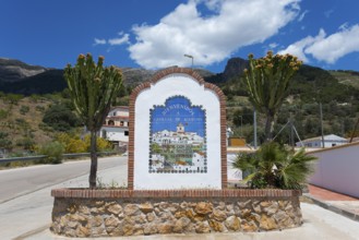 A welcome sign with colourful flowers and cacti in the foreground, surrounded by mountains under a
