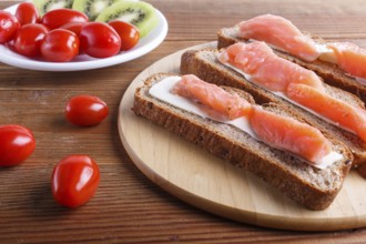 Smoked salmon sandwiches with butter on wooden background. cherry tomatoes. top view, close up