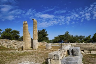 Two ancient columns amidst ruins and stone walls under a clear blue sky, Temple of Apollo, Kamiros,