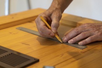 Hands using a ruler and drawing lines on wood in close-up
