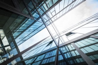 Mirrored modern building façades rise into the sky, reflecting blue and white, University of